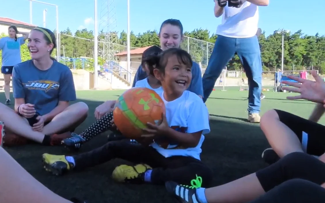 A child smiling with a soccer ball during Lauren's previous JBU mission service in Guatemala